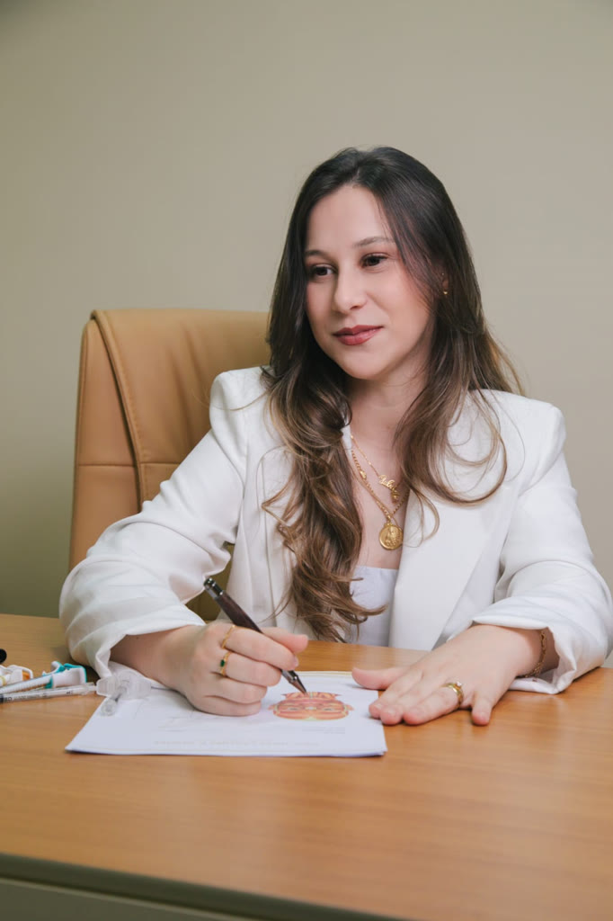 Dra. Júlia de blazer branco planejando sobre uma ilustração facial